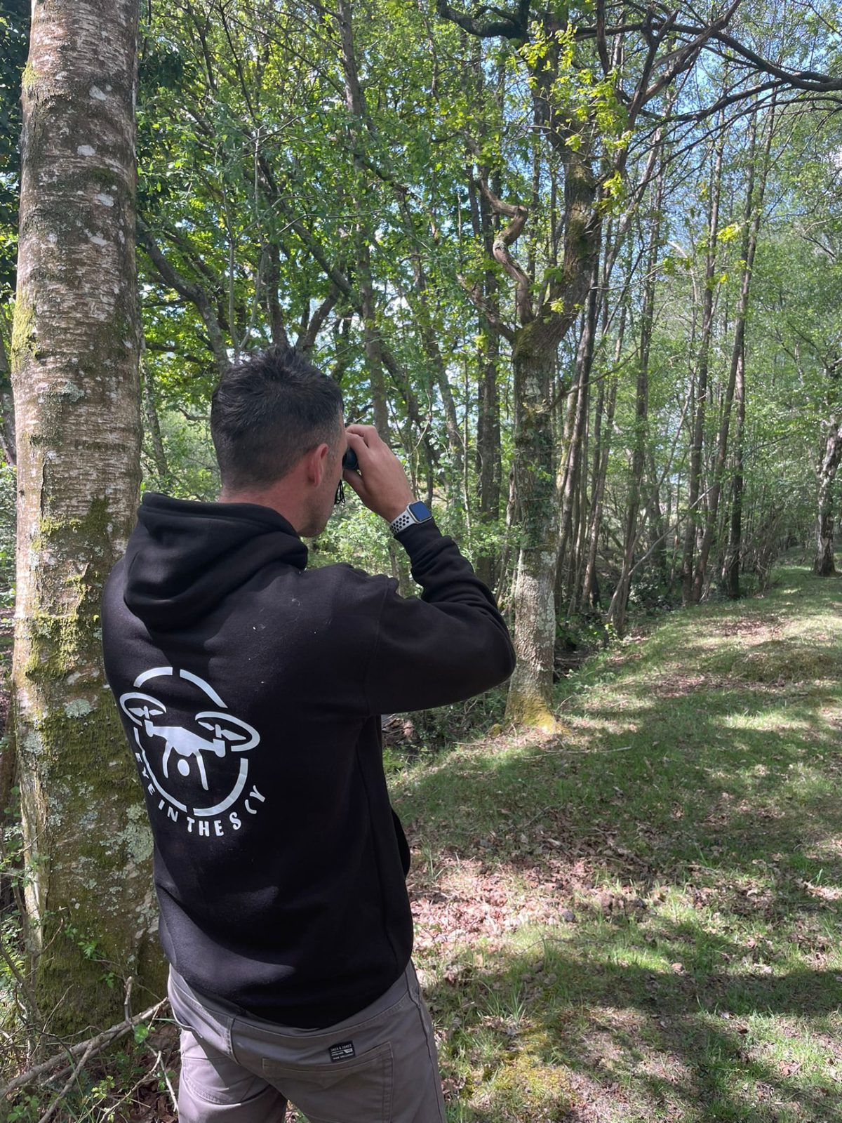 Dave Rimmer searching woodland with binoculars